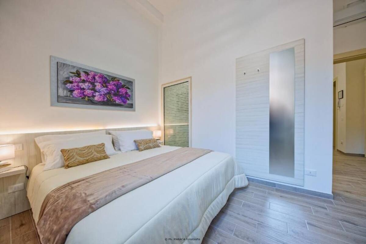 Quarto com uma cama grande, uma mesa de cabeceira, um quadro na parede e uma porta de correr.