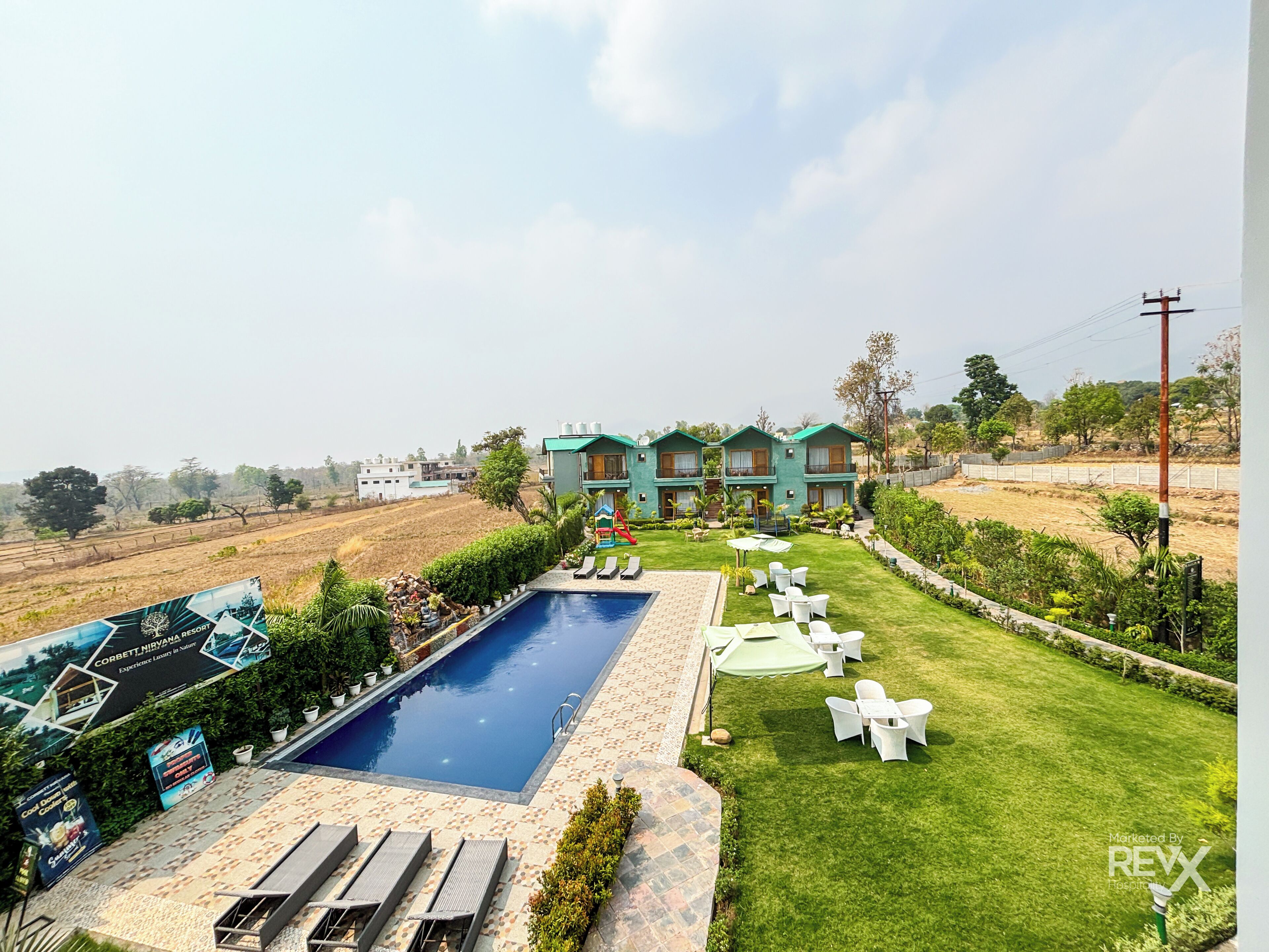 A resort with a swimming pool, outdoor seating, and a view of the surrounding landscape.