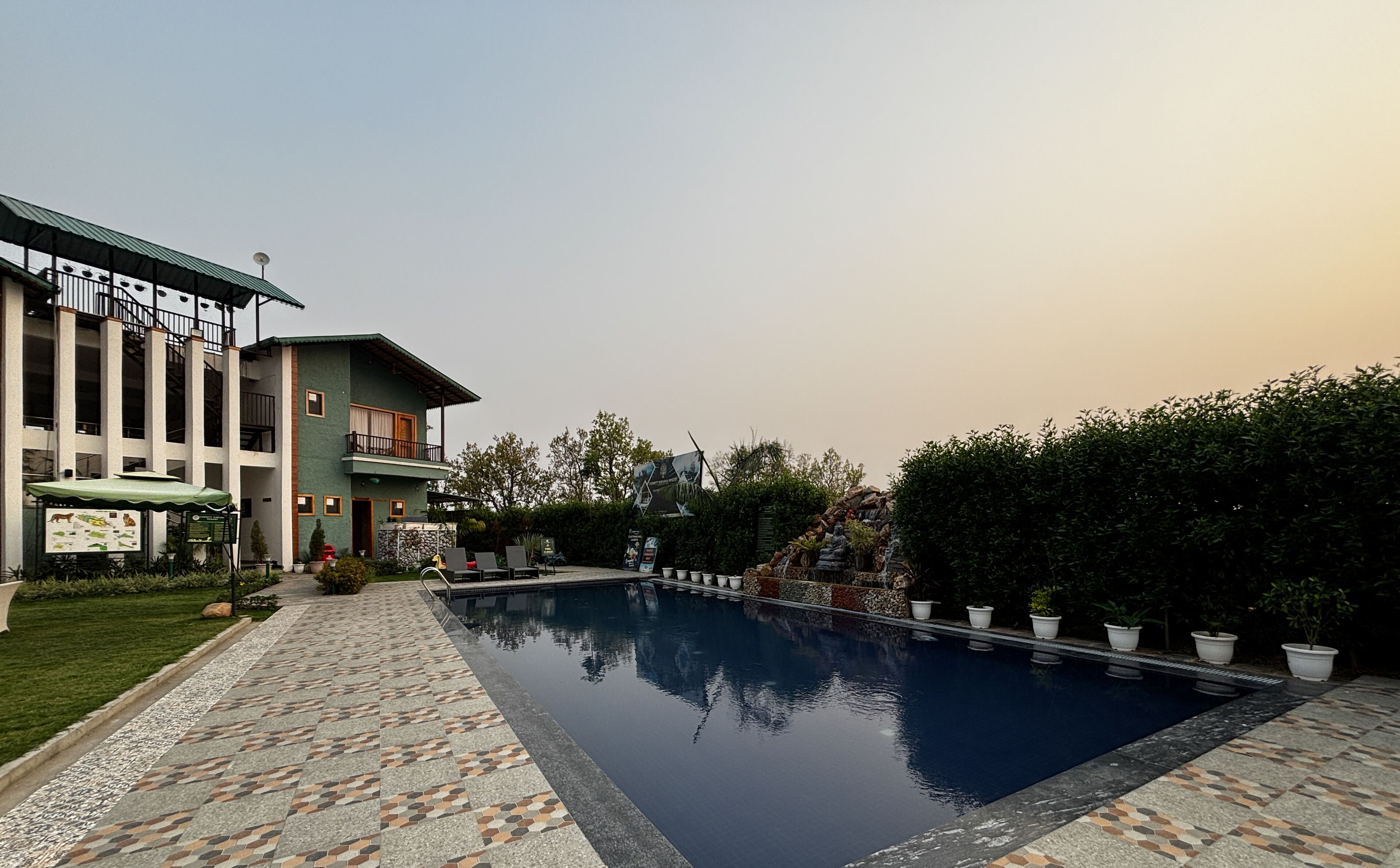 A modern building with a swimming pool, a covered outdoor seating area, and a landscaped garden.