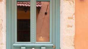A teal door with a window, a small porch, and a round doorknob.
