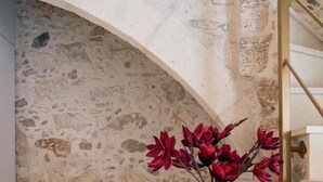 A stone staircase with a metal railing, a wooden chair, and a table with a vase of flowers.