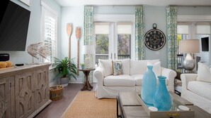A living room with a white sofa, a wooden cabinet, a TV, and decorative items.