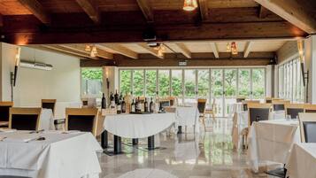 Un restaurante con vigas de madera, ventanas amplias y mesas dispuestas para comer.