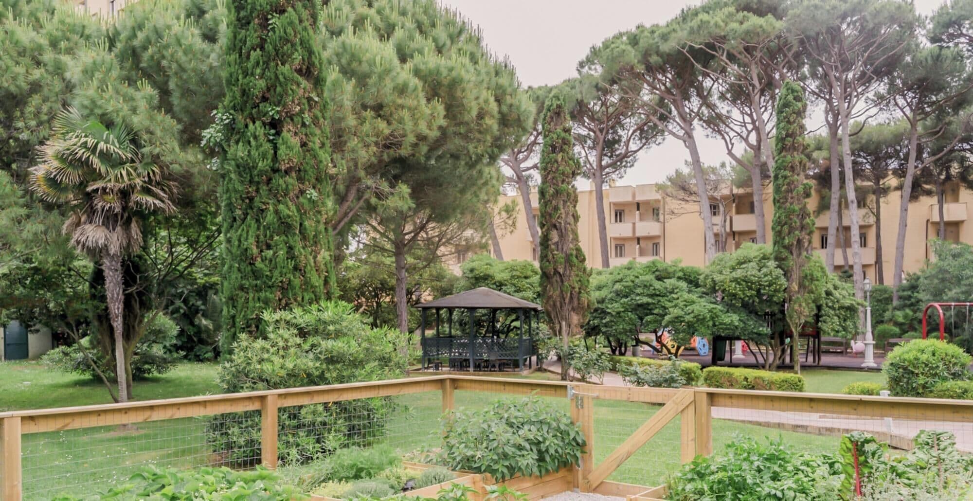 A park with a gazebo, trees, and a building in the background.