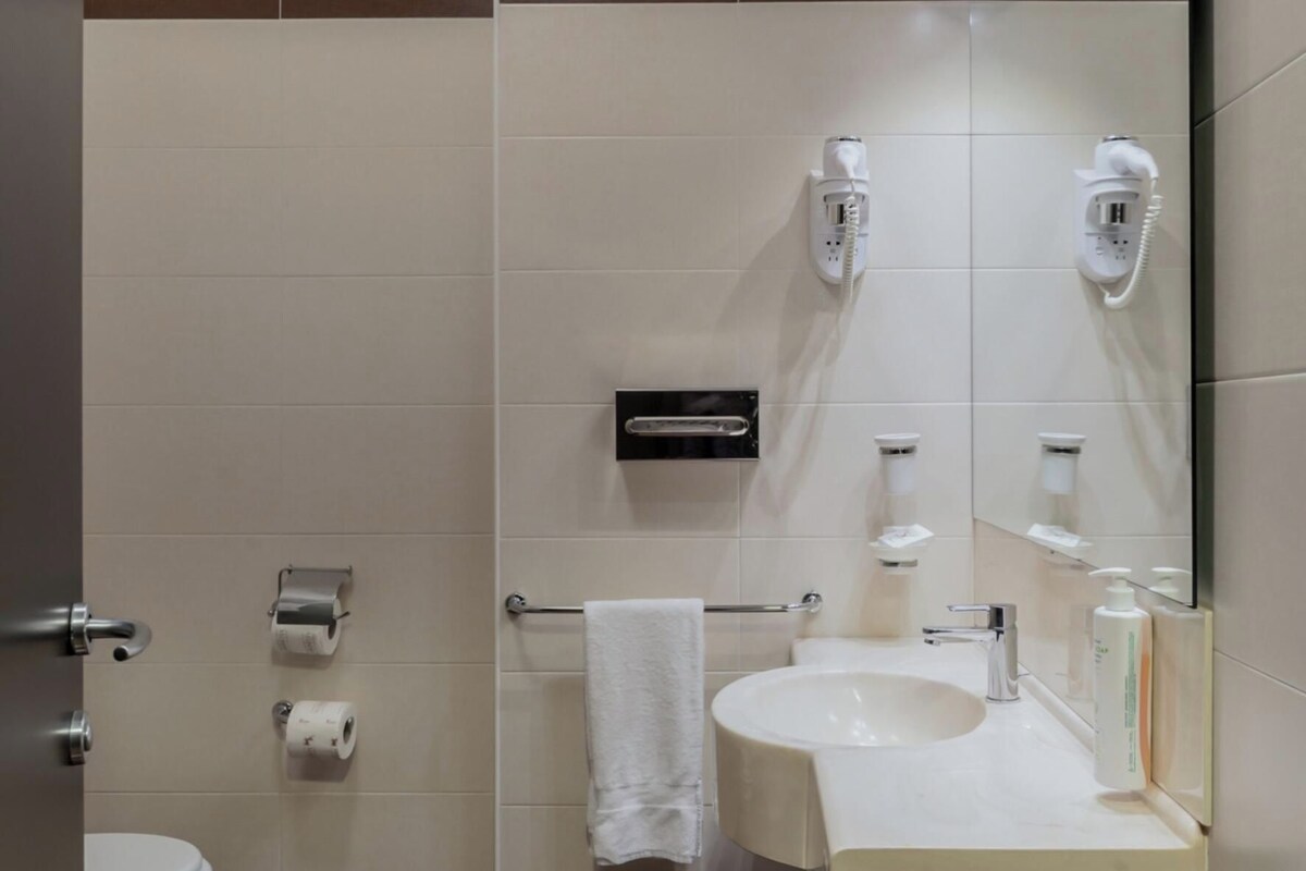 Une salle de bain d’hôtel équipée de toilettes, d’un lavabo, d’un porte-serviettes et d’un miroir.