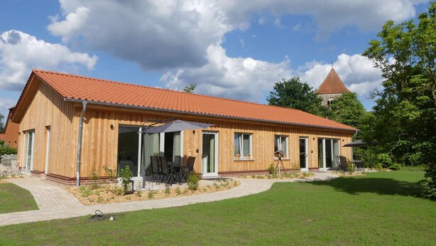 A wooden building with a red-tiled roof, large windows, and a covered patio area. - Alpaca Lodge Kirchwahlingen (Kirchwahlingen)