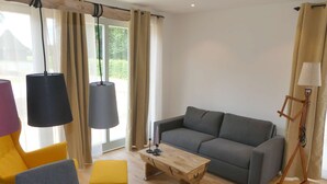 A modern living room with a grey sofa, wooden coffee table, and yellow and grey chairs. - Alpaca Lodge Kirchwahlingen (Kirchwahlingen)