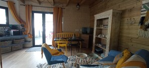 Un salon confortable avec un canapé, des fauteuils, une table et un téléviseur.