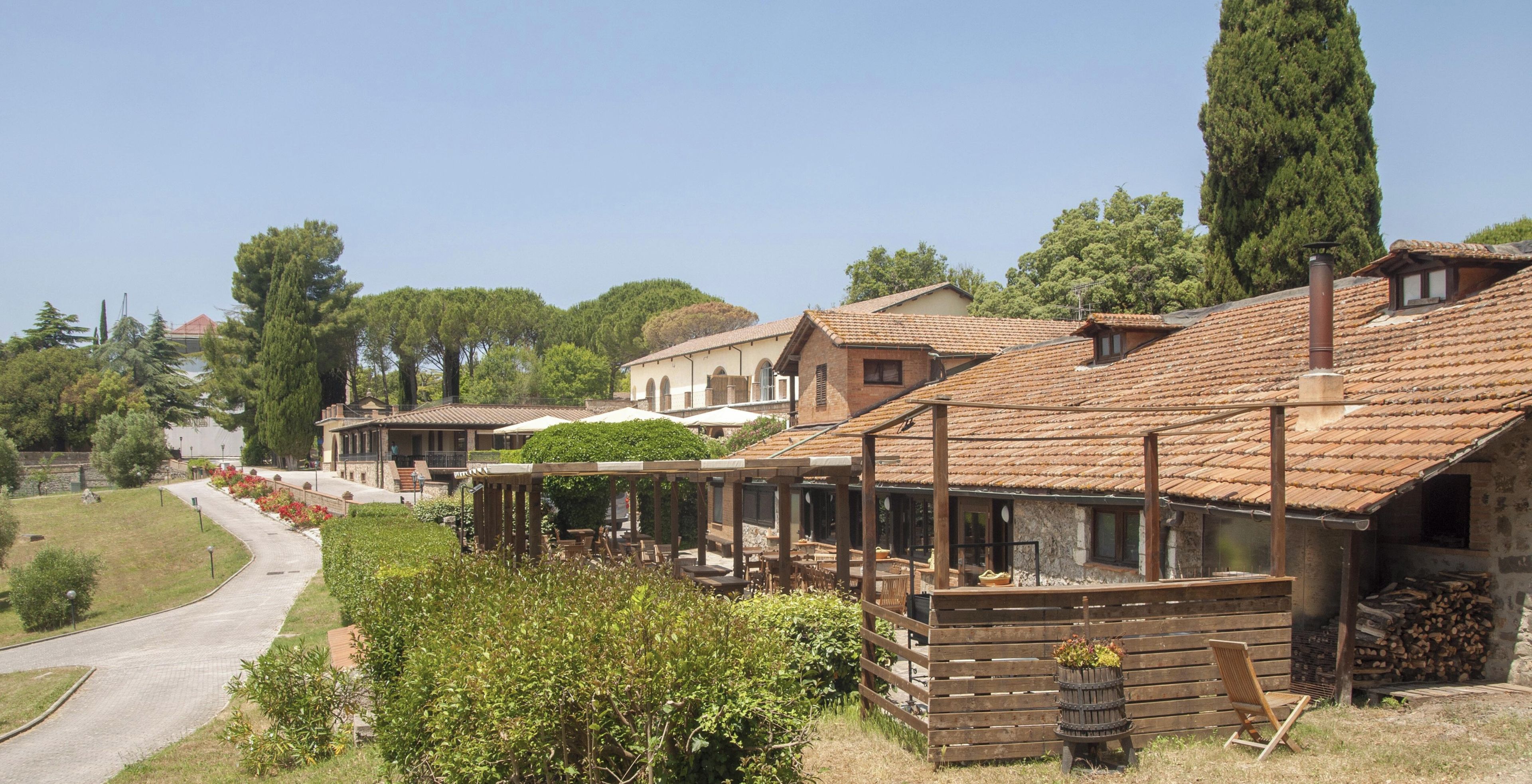 A traditional building with a tiled roof, wooden benches, and a garden area with a pathway.