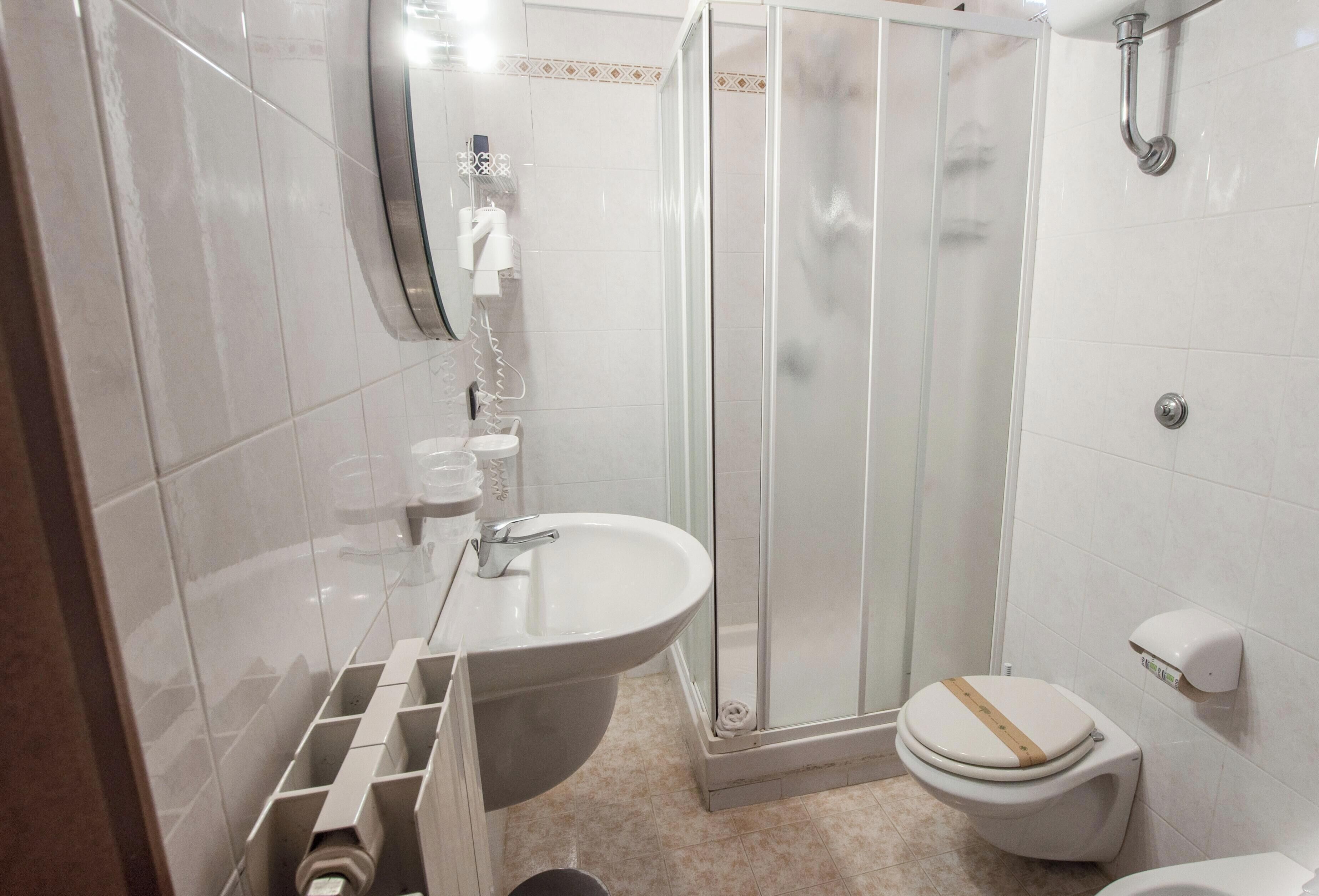 Ein Badezimmer mit Dusche, Toilette, Waschbecken und Spiegel.