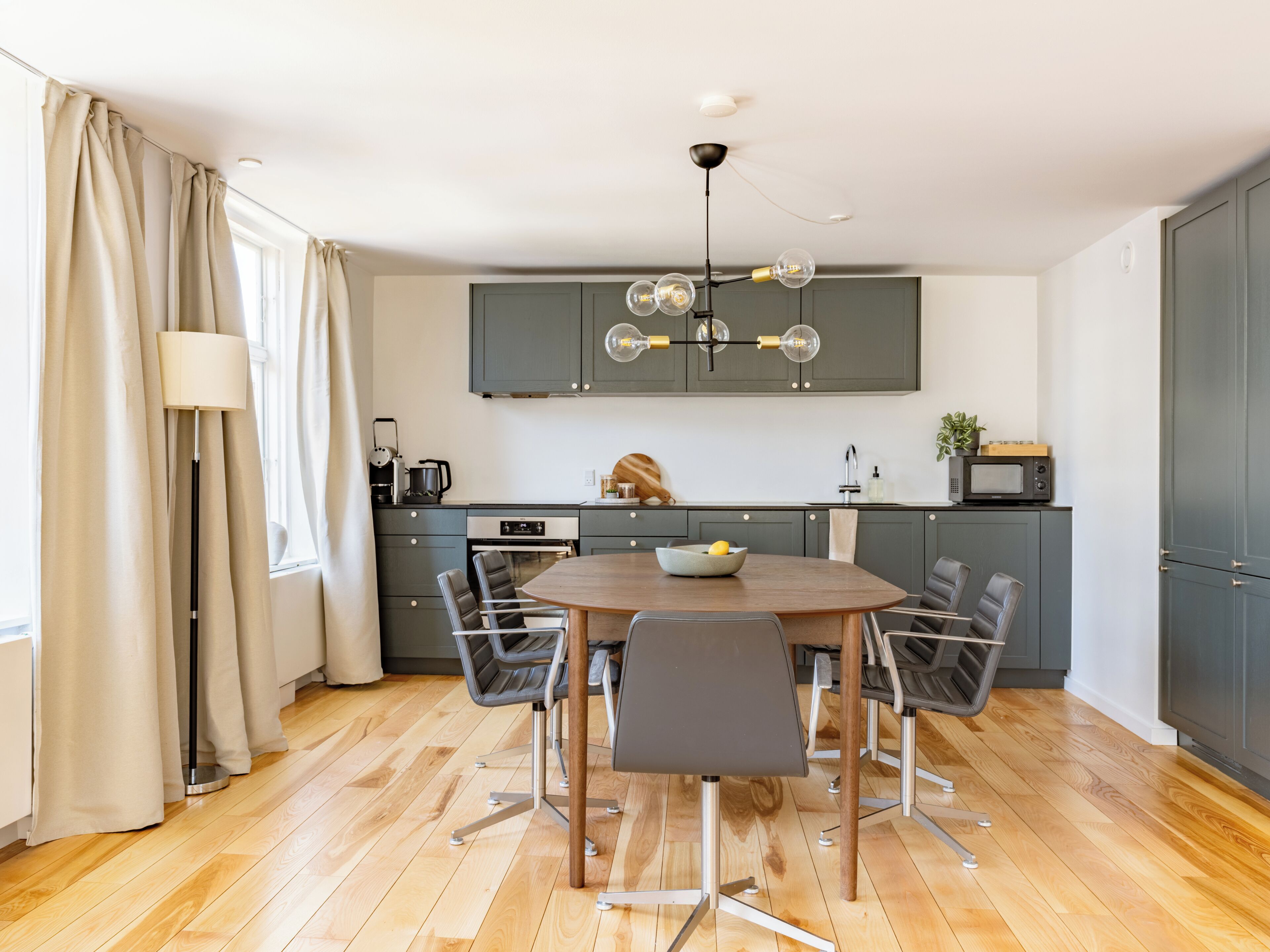 A modern kitchen with a dining table, chairs, and a chandelier.