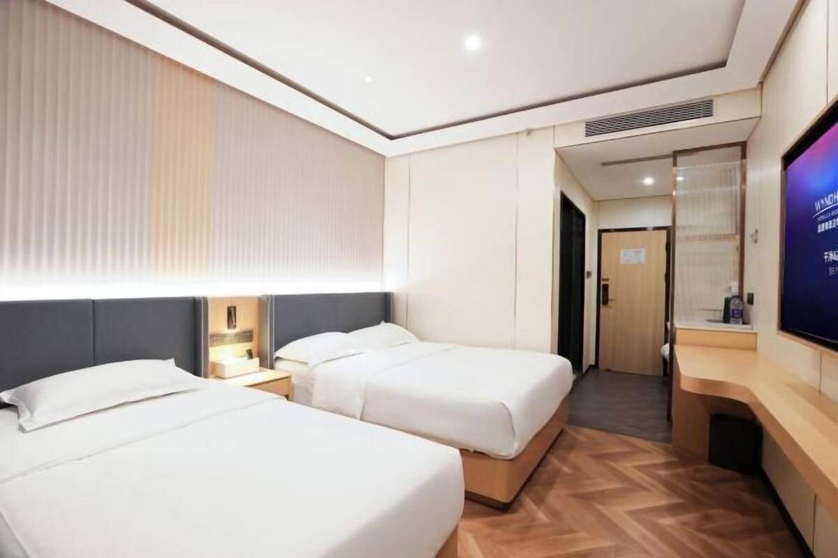A hotel room with two beds, a TV, a desk, and a walk-in closet.
