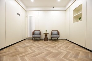 A room with two chairs, a small table, and a radiator.