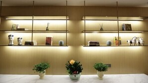 A hotel reception area with a marble counter, two potted plants, and shelves with books and decorative items. - Super8 Yuet Hotel (Beijing Qilizhuang Branch) (Beijing)