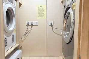 A laundry room with two washing machines, electrical outlets, and a sign on the wall. - Super8 Yuet Hotel (Beijing Qilizhuang Branch) (Beijing)