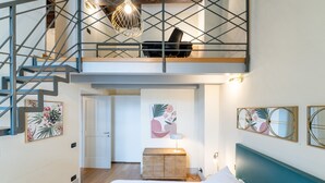 A bedroom with a bed, a nightstand, a desk, a chair, a staircase, and artwork on the walls. - Palazzo Odescalchi by Wonderful Italy - Apt 6 (Como)