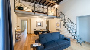 A modern living space with a staircase, a sofa, a dining area, and a staircase with a metal railing. - Palazzo Odescalchi by Wonderful Italy - Apt 6 (Como)