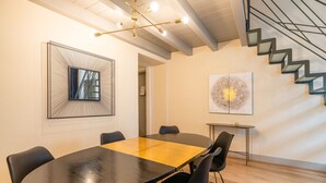 A modern meeting room with a wooden table, black chairs, a large abstract painting, and a staircase. - Palazzo Odescalchi by Wonderful Italy - Apt 6 (Como)