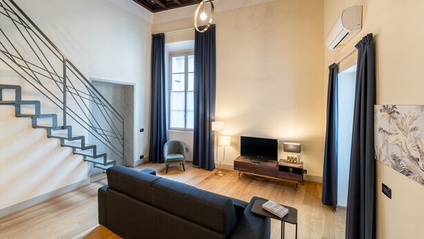 A modern living room with a staircase, a sofa, a TV, and a lamp. - Palazzo Odescalchi by Wonderful Italy - Apt 6 (Como)