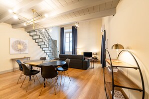 Un interior moderno con comedor, escalera, sala de estar y un gran ventanal.