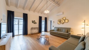 Un salon spacieux avec un plancher en bois, un canapé, une table basse et un téléviseur.