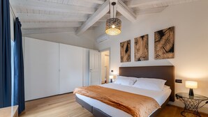 Une chambre avec un lit, un plancher en bois, un ventilateur de plafond et des œuvres d’art murales.