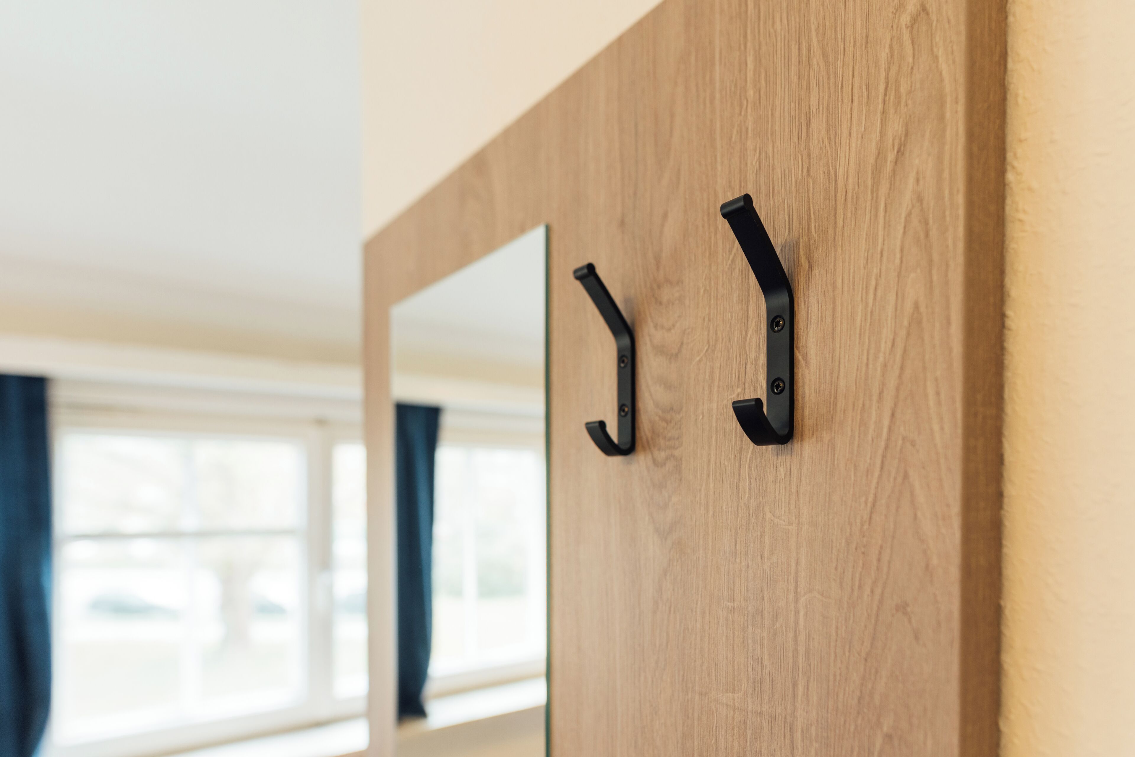 A wooden door with two black metal hooks.