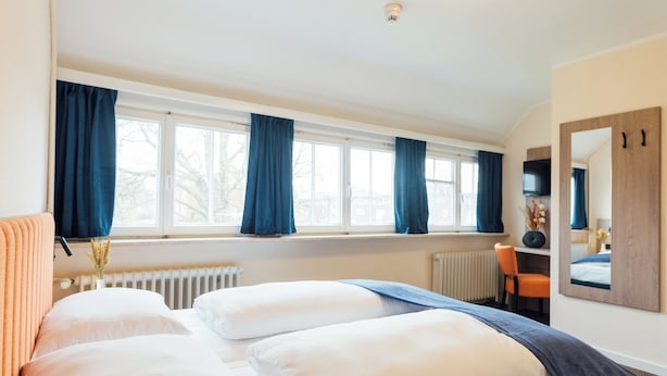 A hotel room with a large bed, a desk, and a window with curtains. - Myky Hotel Pinneberg (Pinneberg)