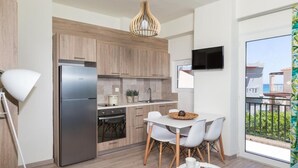 A modern kitchen with a stainless steel refrigerator, wooden cabinets, and a dining area with a table and chairs. - Anemi Blue apt-close to the beach (Rethymno)
