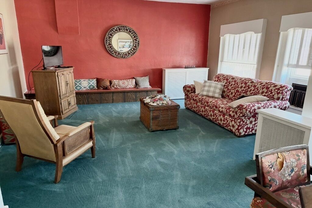 A living room with a red wall, a sofa, a chair, a small table, and a cabinet.