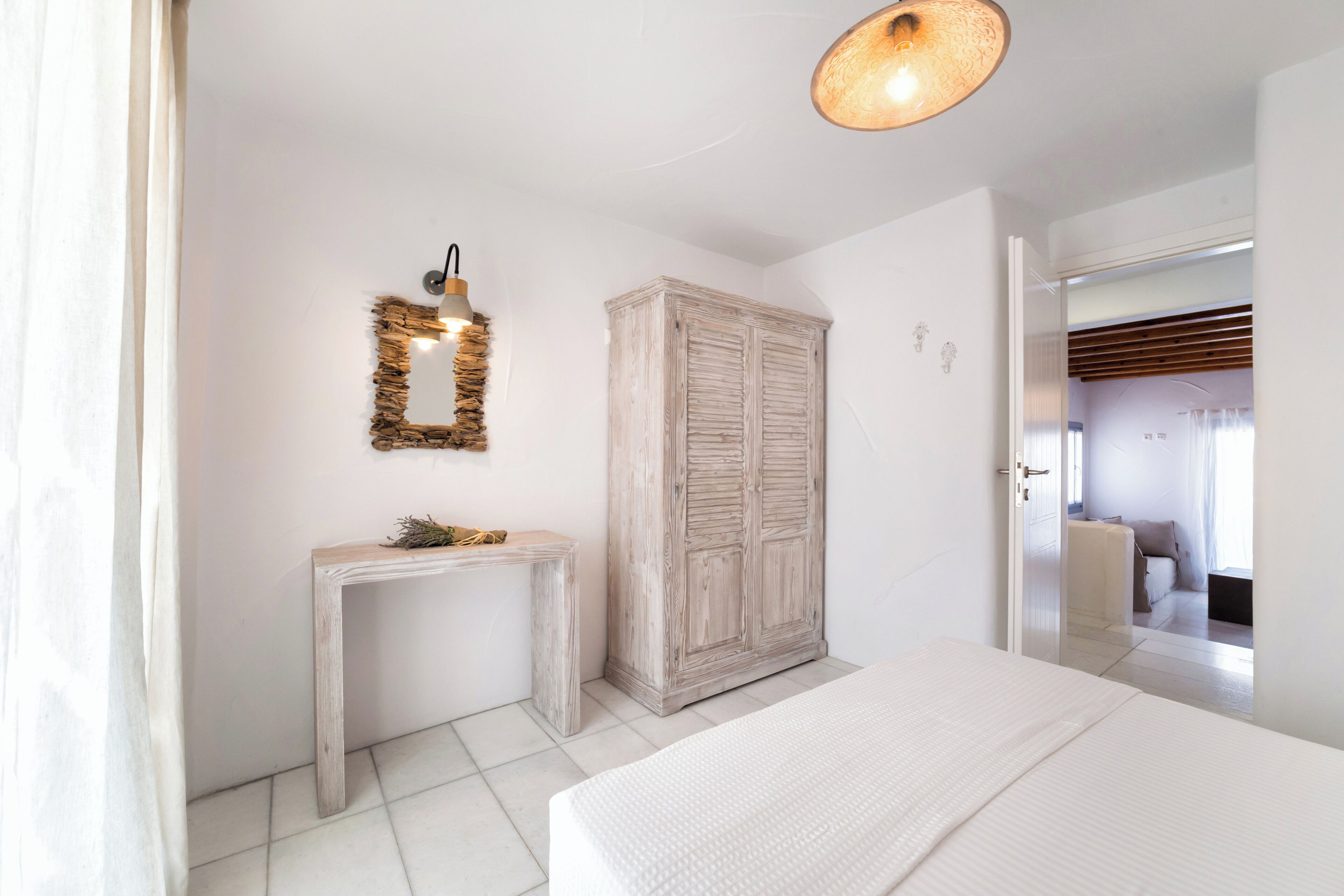A bedroom with a bed, a wooden wardrobe, a console table, and a wall-mounted mirror.