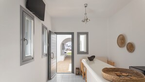 Eine moderne Küche mit weißer Arbeitsplatte, einer hängenden Leuchte und Blick in den Essbereich.