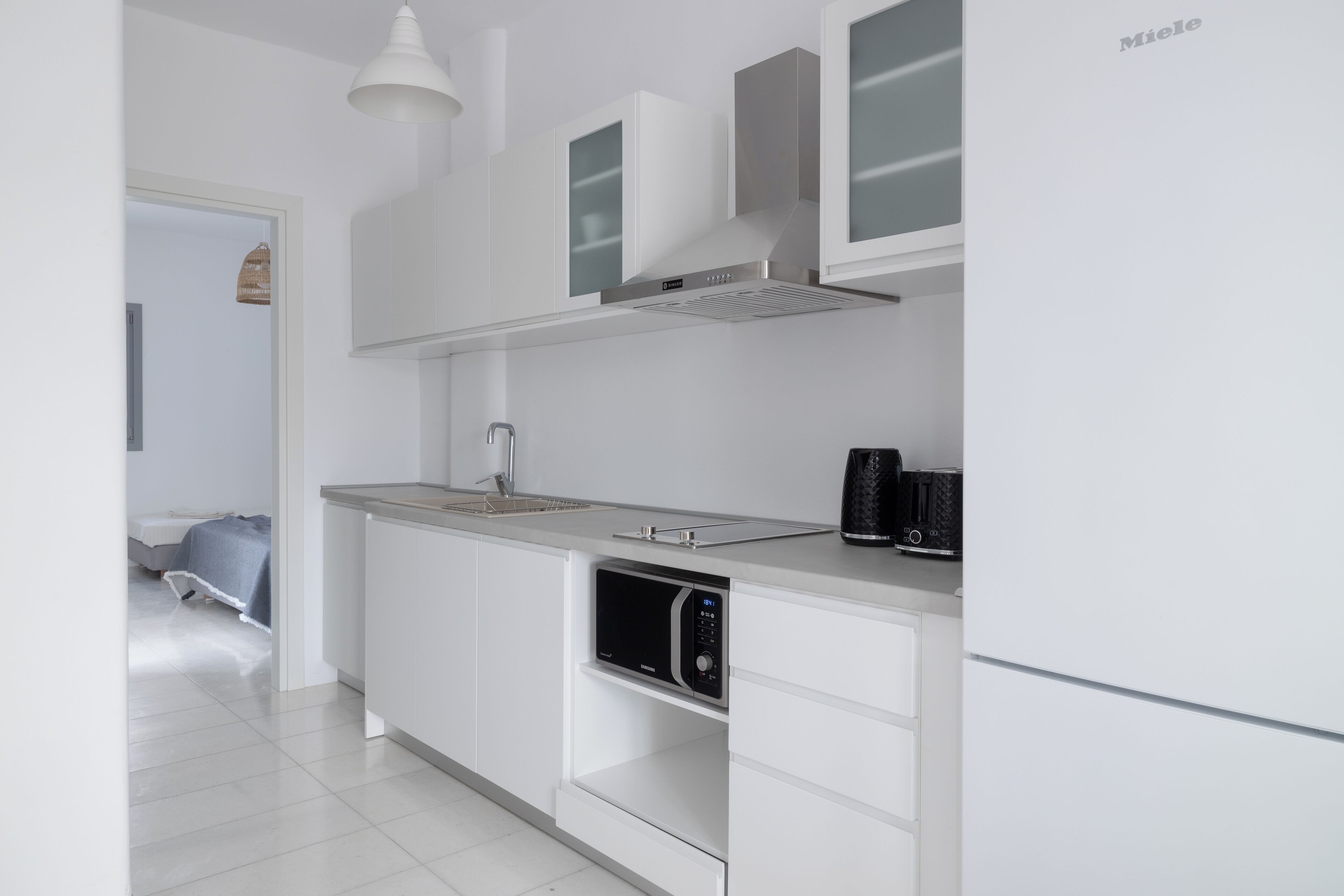A modern kitchen with white cabinetry, a built-in microwave, and a coffee maker on the counter.