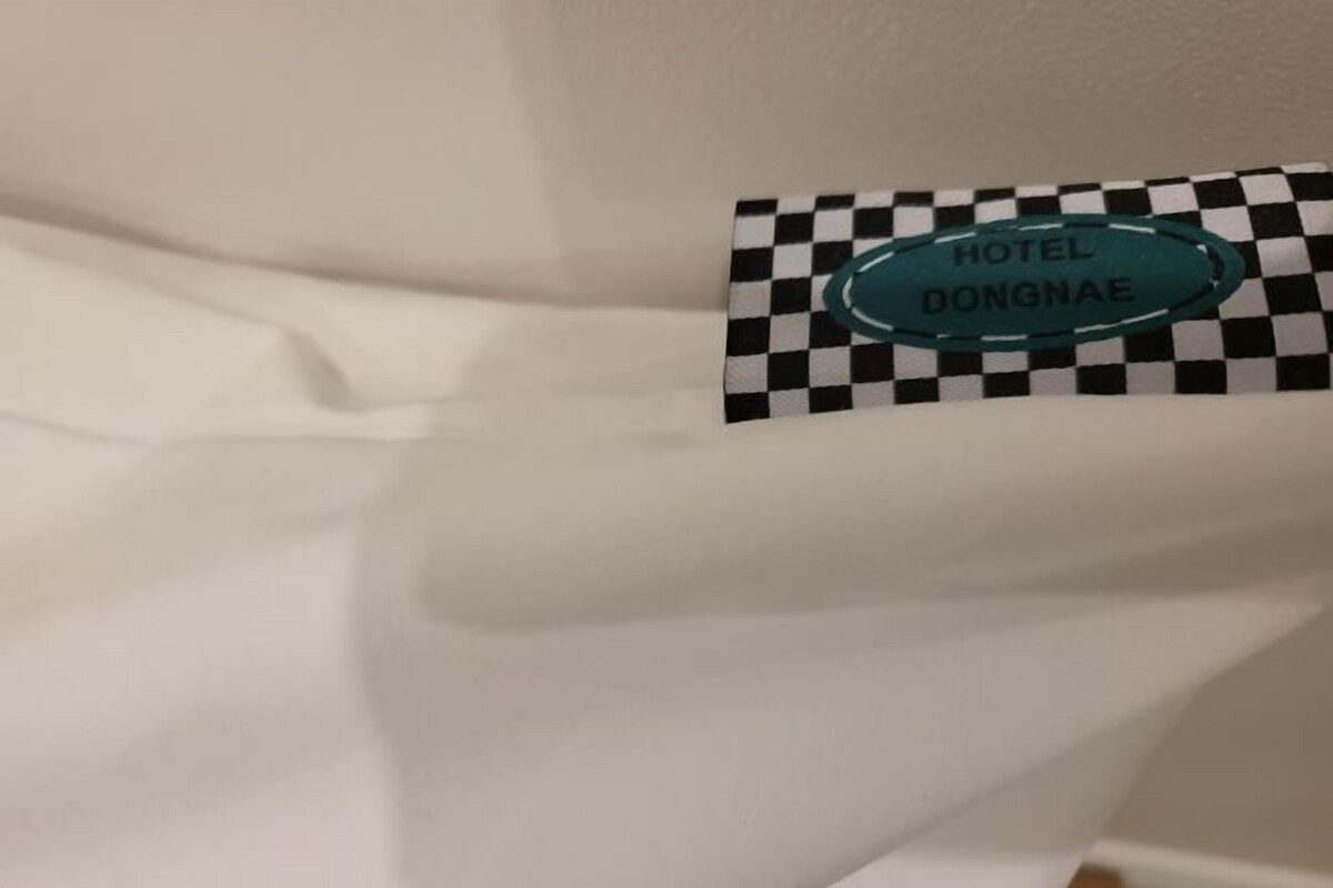 Tecido branco com etiqueta xadrez que diz 'HOTEL DONGNAE'.