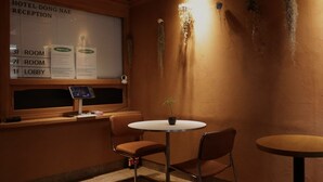 A hotel reception area with a reception desk, a digital display, and a wall-mounted sign indicating room numbers. - Hotel Dongnae (Busan)