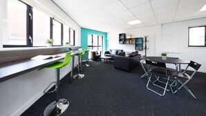 A modern office space with a long desk, green chairs, a sofa, and a dining table. - For Students Only Prospect Point in Liverpool (Liverpool)