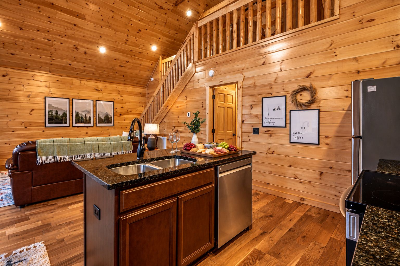 A wooden cabin interior with a kitchen island, wooden floors, and a staircase.