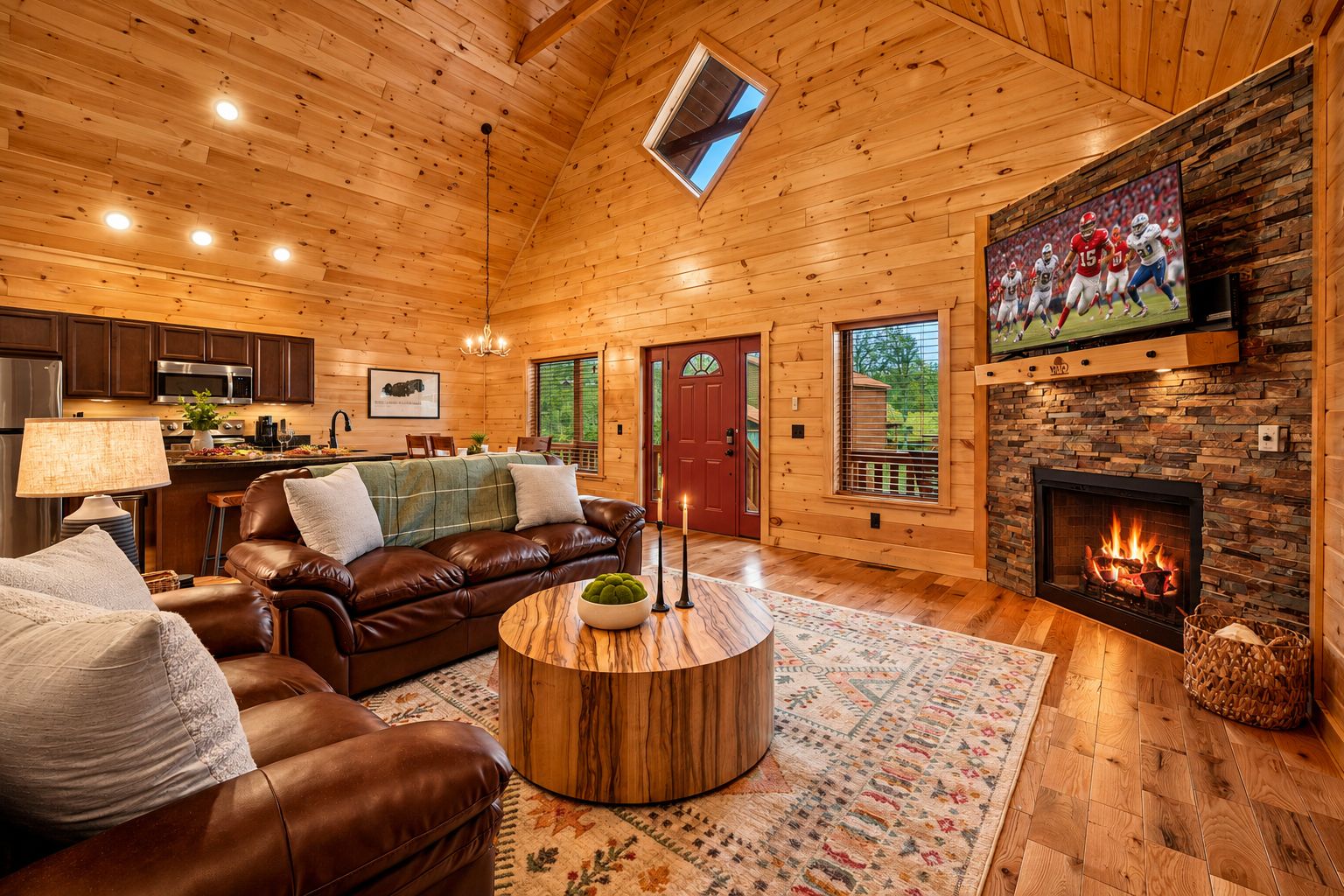 L’intérieur chaleureux d’un chalet avec une cheminée, un canapé en cuir, une table à manger en bois et un coin cuisine.