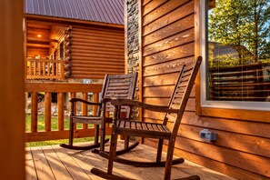 Een houten terras met schommelstoelen en een stenen muur.