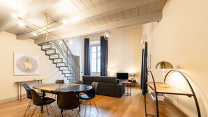 Un espacio moderno con comedor, sofá, escalera y estantería.