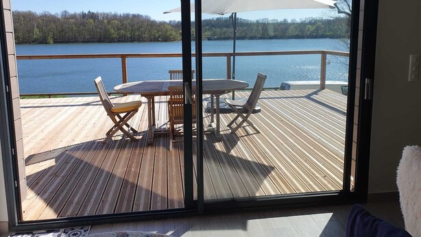 Una terrazza con tavolo e sedie, con vista su un lago.