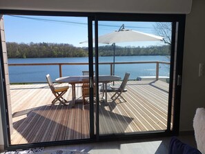 A deck with a table and chairs, overlooking a lake. - New chalet with direct view of Lac de Charmes (Changey)