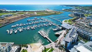 A marina with multiple docks and boats, surrounded by buildings and a clear blue sky.