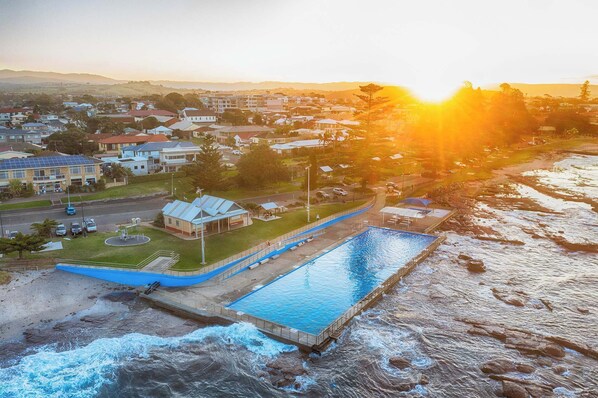 A residential area with a swimming pool adjacent to a rocky shoreline.