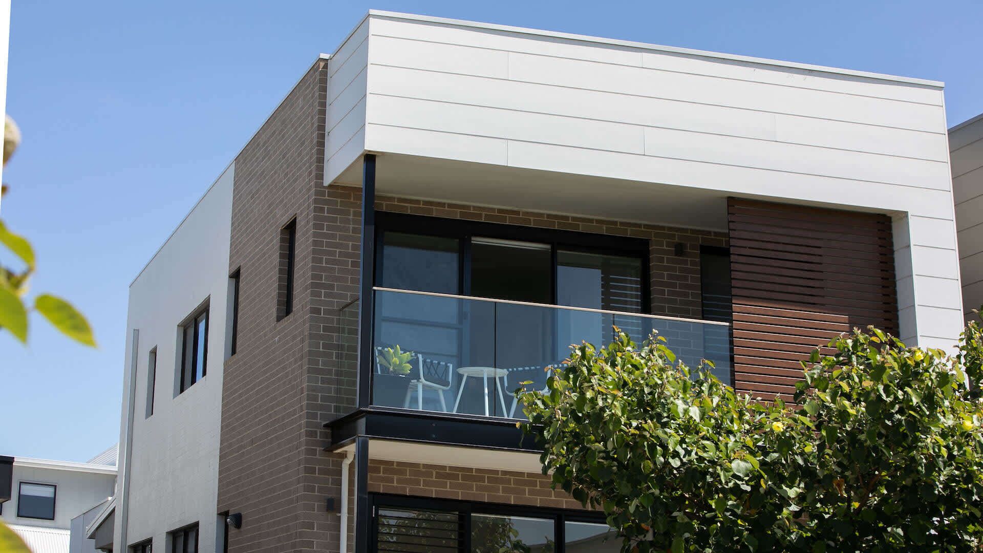 Un bâtiment moderne à deux étages, doté d’un balcon, de grandes fenêtres et d’une façade en briques.