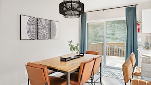 En matplats med ett träbord, bruna stolar och en svart hänglampa.