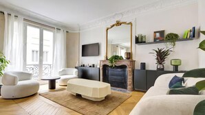 Un salon moderne doté d’une cheminée, d’un téléviseur à écran plat et d’un balcon agrémenté de rideaux blancs.