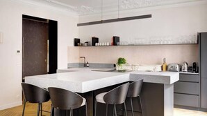 Une cuisine moderne dotée d’un grand îlot central, de tabourets de bar, d’un évier et d’un plan de travail sur lequel sont disposés divers appareils électroménagers.