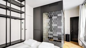 Une chambre moderne avec un lit, une armoire, un mur en blocs de verre et une porte.
