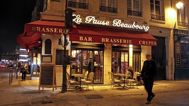 Vue nocturne de La Pause Beaubourg, un bar-restaurant doté d’une terrasse.